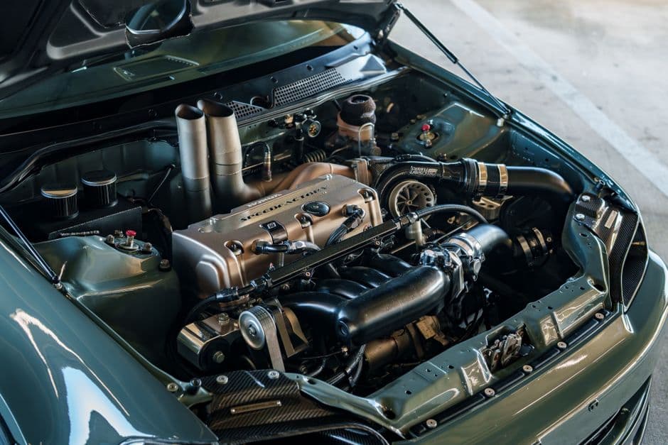 Aftermarket turbo kit installed in a modified engine bay with charge piping and intercooler hardware visible