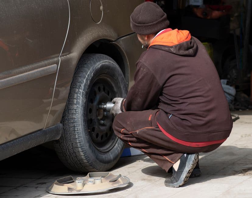 Mechanic changing a car wheel to inspect the hub and wheel bearing