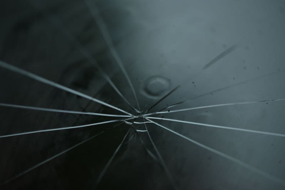 Close-up of cracked windshield glass with radiating lines from a rock chip impact point